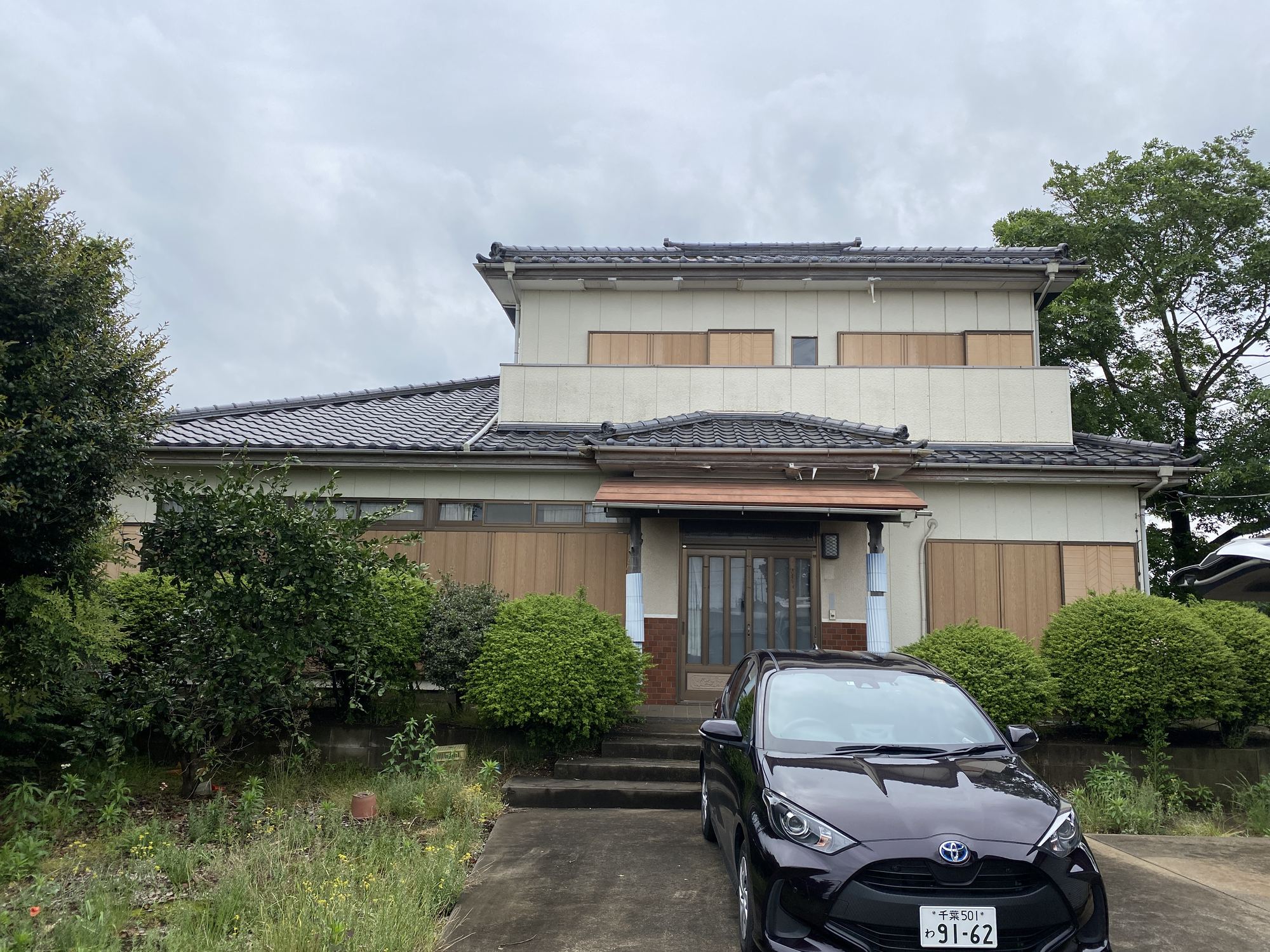 買取時の本社（草に覆われた庭と色あせた外壁）